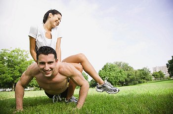 a man does push-ups while woman sits on his back