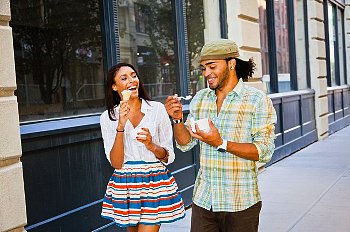 A young couple walks down the street eating ice cream