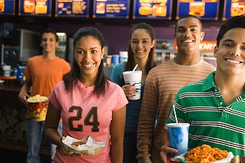A group of young people stand in front of a fast food counter with food.