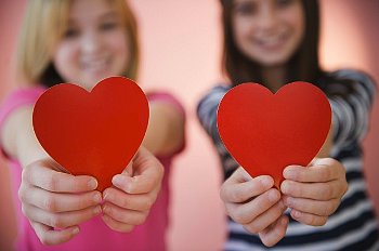 Young women hold up heart cut-outs