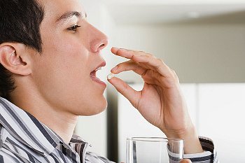 Man in stripped shirt puts pill into this mouth