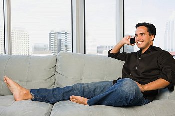 A man talking on the phone while sitting on his sofa