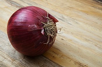 A purple onion sits on a wooden table