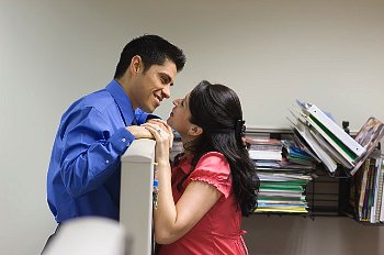 Co-workers get close over cubicle partition at work