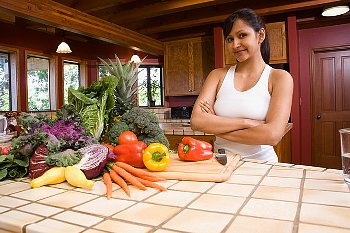 A woman stands beside a counter top with fresh vegetables