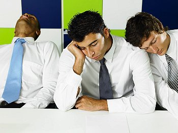 Three young men fall asleep on their arms in a professional setting