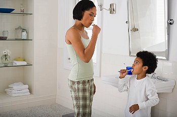A mother and her son brush their teeth in the bathroom