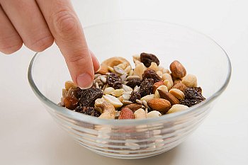 person is picking up nuts from a glass bowl
