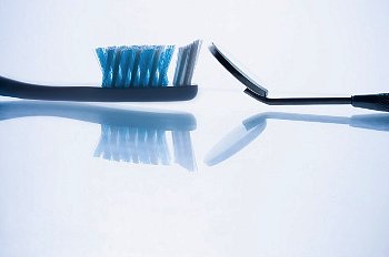 Tooth brush and mirror sit on a table