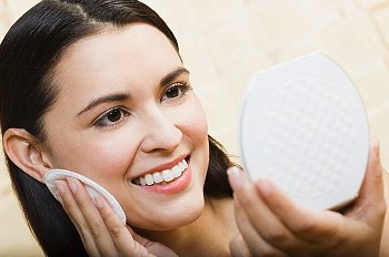 Smiling woman looks into compact mirror