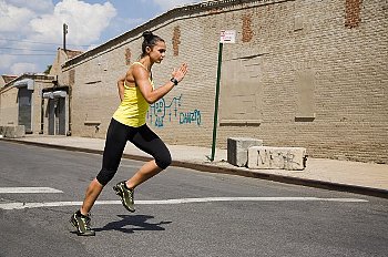 Woman in yellow tanktop running with urban background