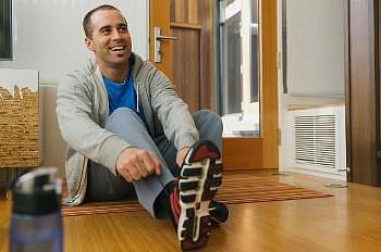 Man sitting on floor trying on running shoes