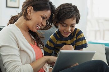 Mother and son learn together on the couch on a digital tablet