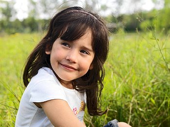 Little girl sitting in grass smiling