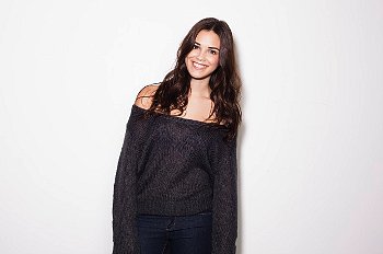 Young woman standing against white background in black sweater