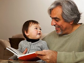A grandfather reading to a granddaughter
