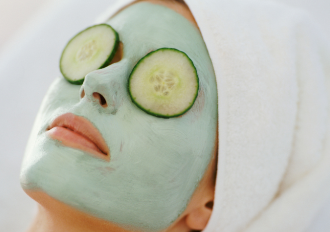 A woman wearing a face mask and cucumber slices on her eyes