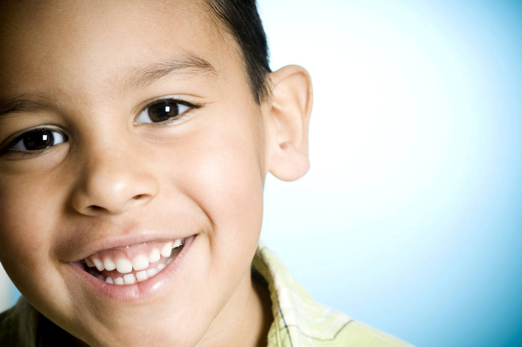 A little boy smiling against a blue background