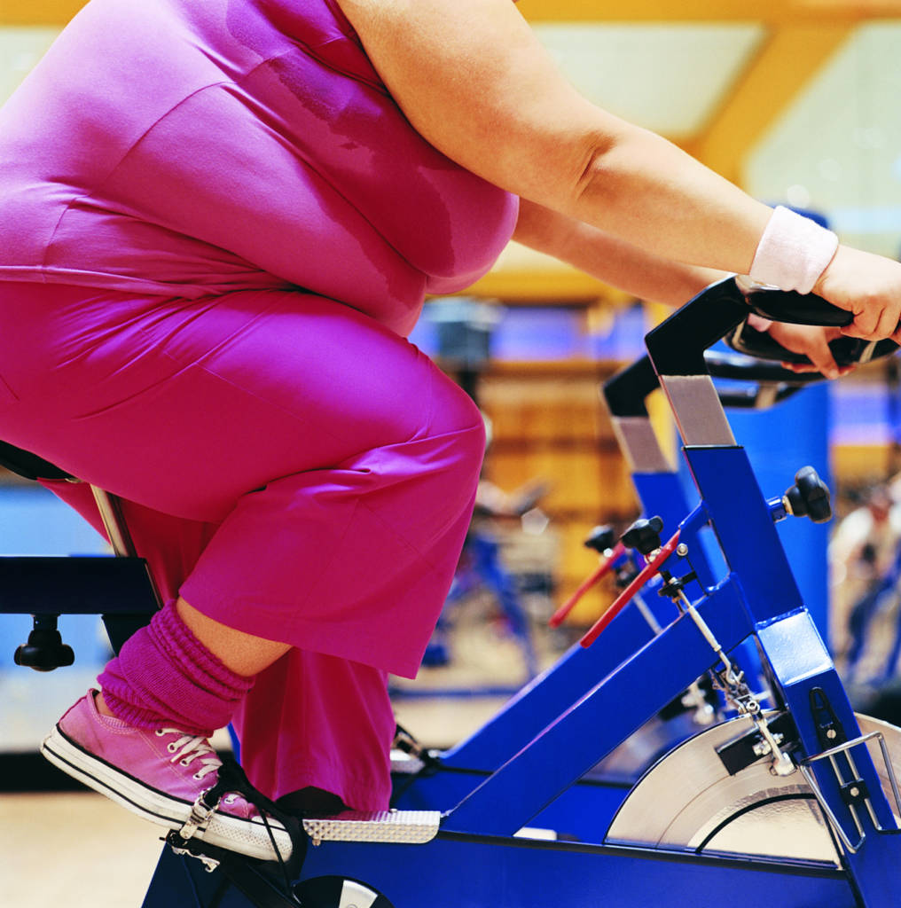 overweight woman, overweight woman riding bicycle, woman at a gym,