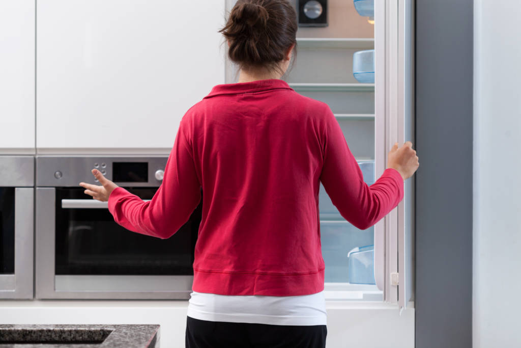 woman opening empty fridge